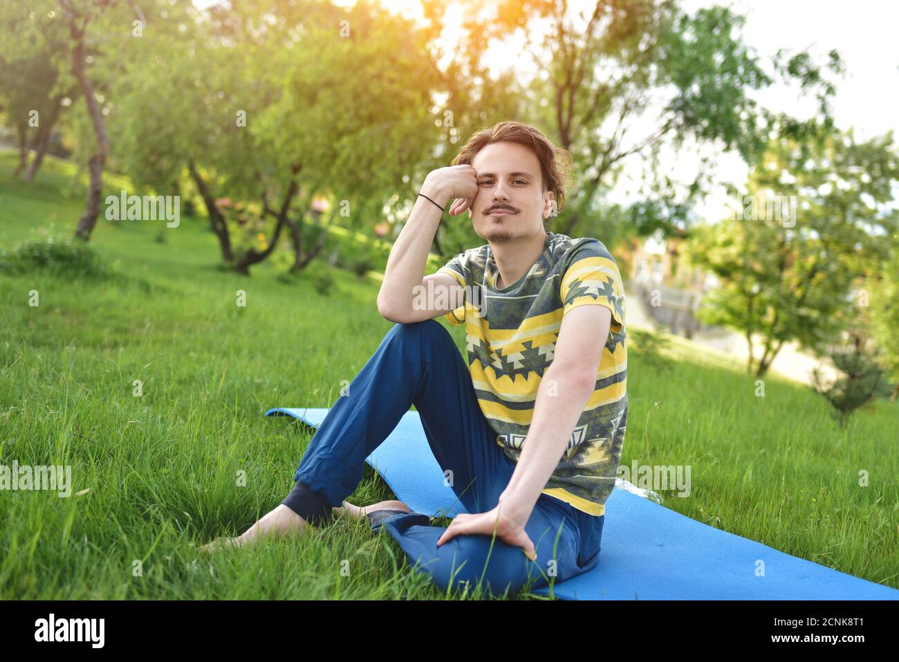 Schöner stilvoller Kerl genießt die Natur und träumt von etwas im Park sitzen. Friedlicher Blick Stockfoto