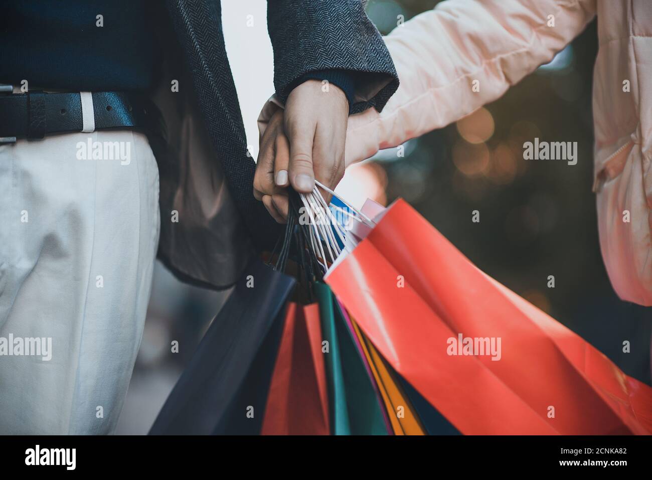 Einkaufstaschen in männlichen und weiblichen Händen. Übergabe von Taschen oder Geschenken, Nahaufnahme. Stockfoto