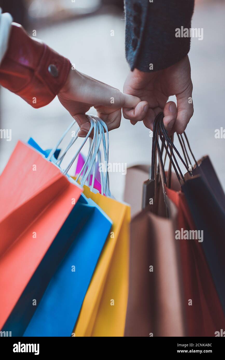 Einkaufstaschen in männlichen und weiblichen Händen. Übergabe von Taschen oder Geschenken, Nahaufnahme. Stockfoto