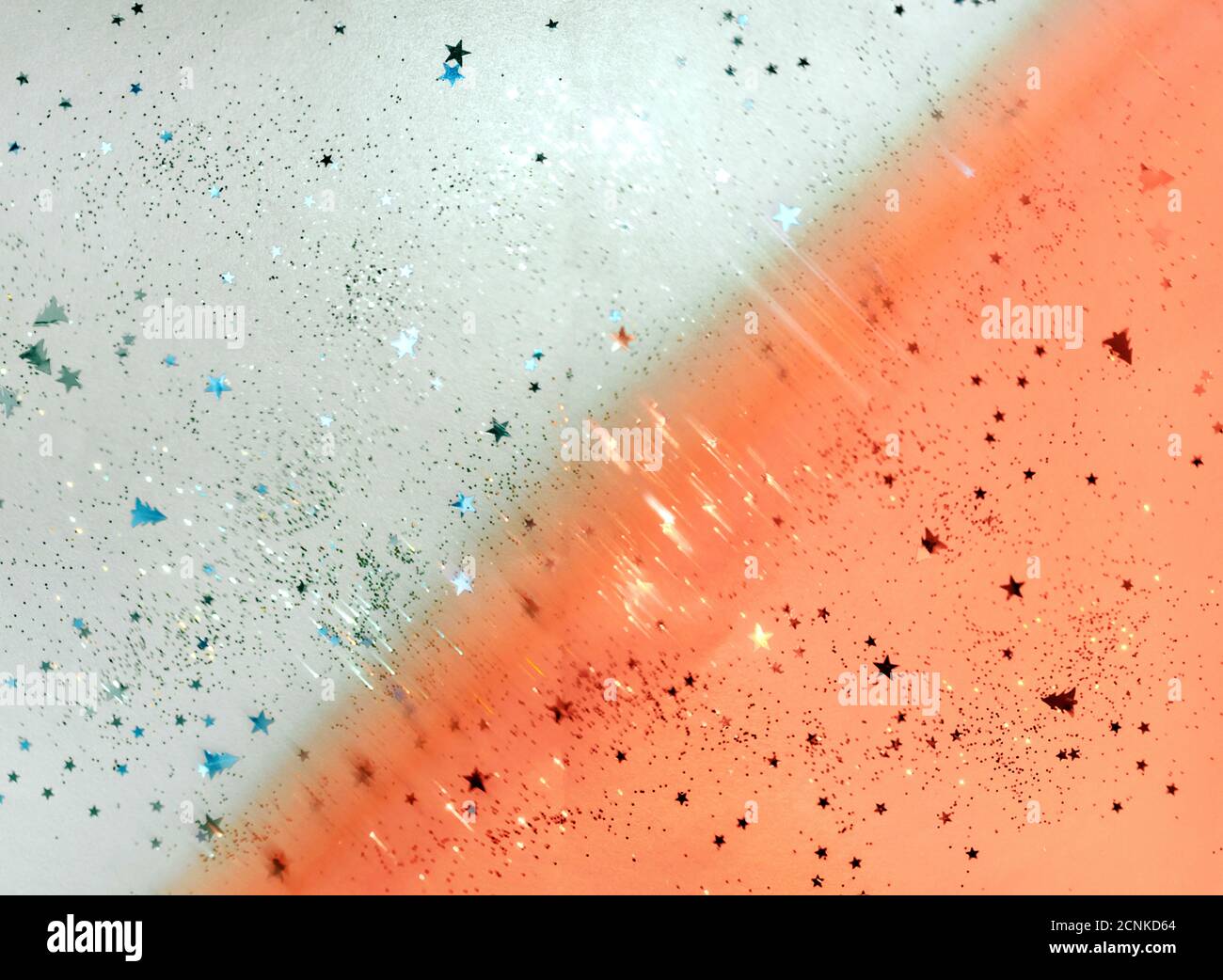 Verstreuter Glitter auf blauem und orangefarbenem Hintergrund, Weihnachten, Neujahrsdekorationen. Stockfoto