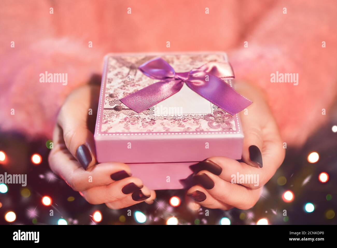 Weibliche Hände halten eine rosa Geschenkbox. Das Thema Valentinstag und Weihnachten Stockfoto