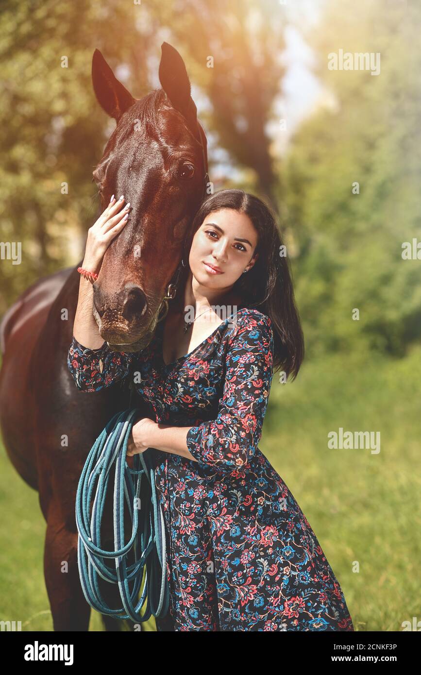 Schöne lateinische Frau in Kleid und ihr schönes Pferd Spaziergang im Wald. Liebe Tiere Konzept. Liebe Pferde Stockfoto