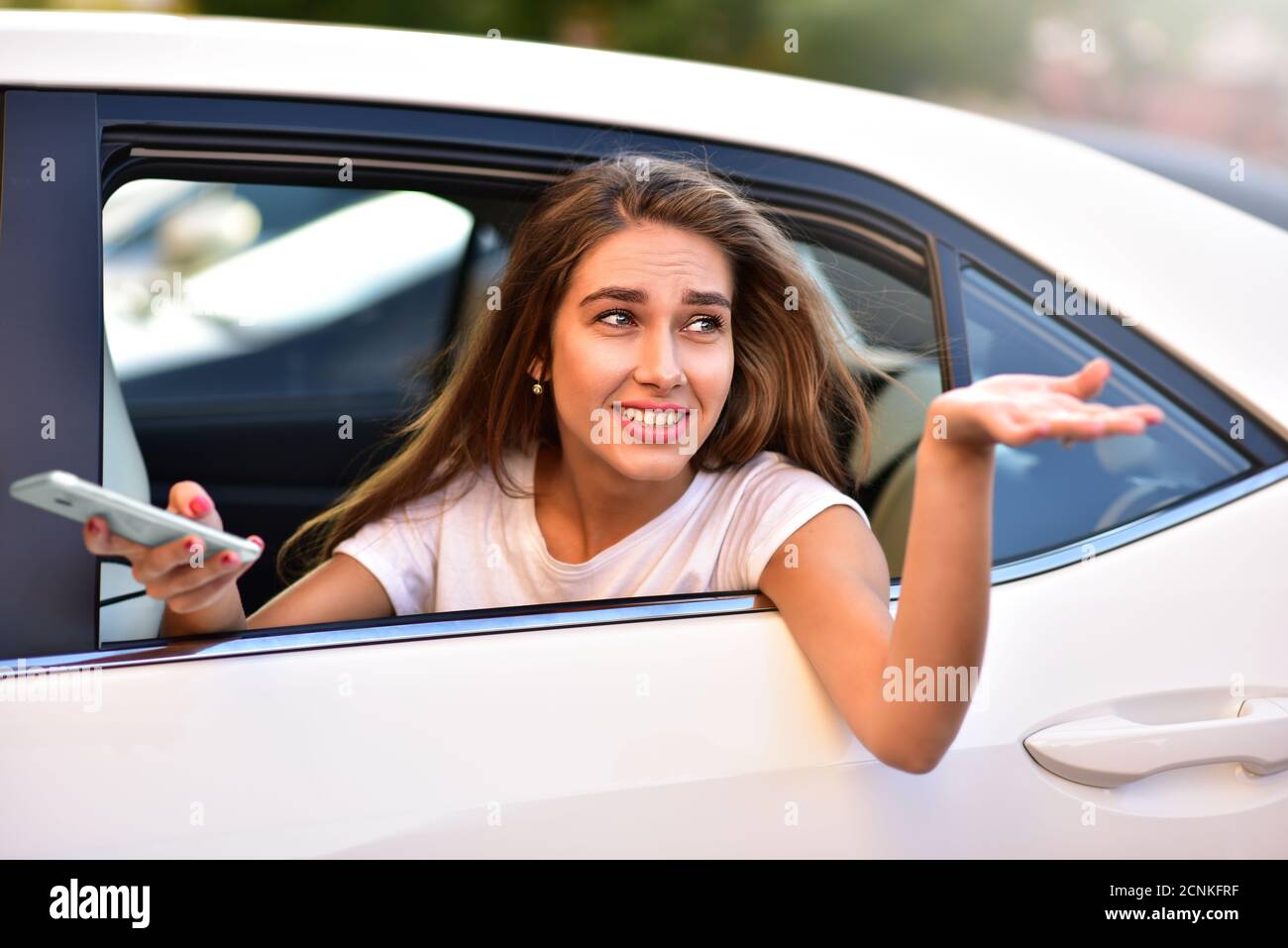 Attraktive Frau mit Telefon im Auto Stockfoto