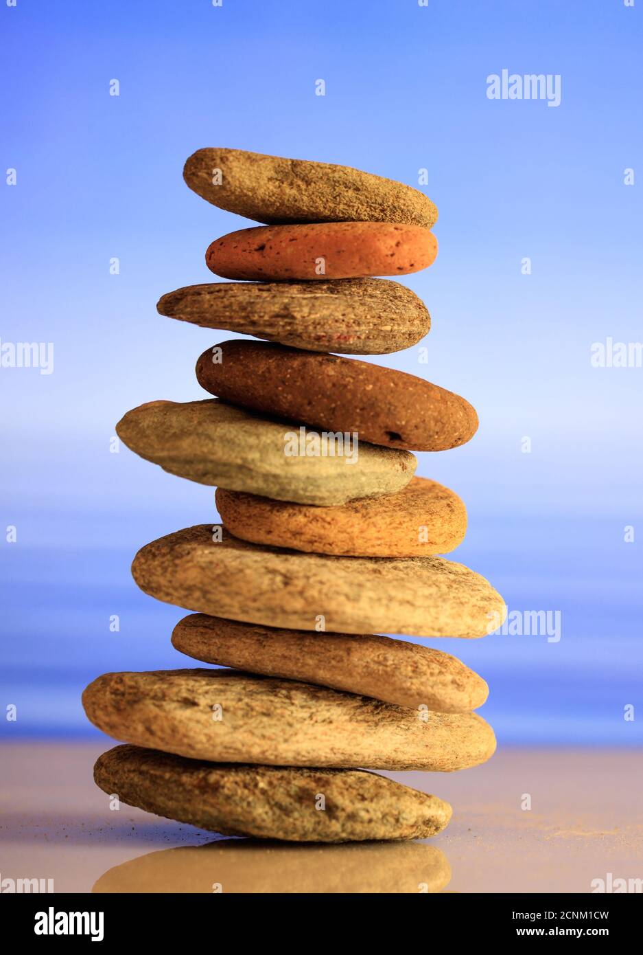 Zen-Steine auf blauem Himmel und Meer Hintergrund gestapelt. Pebbles Turm, Wellness, Spa, Meditation und Entspannung Konzept, vertikal Stockfoto