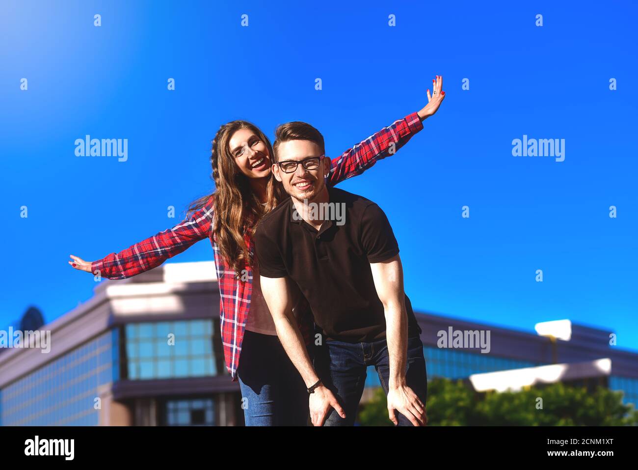 Junge lächelnde Paar mit Spaß Huckepack Reiten auf der Straße. Stockfoto