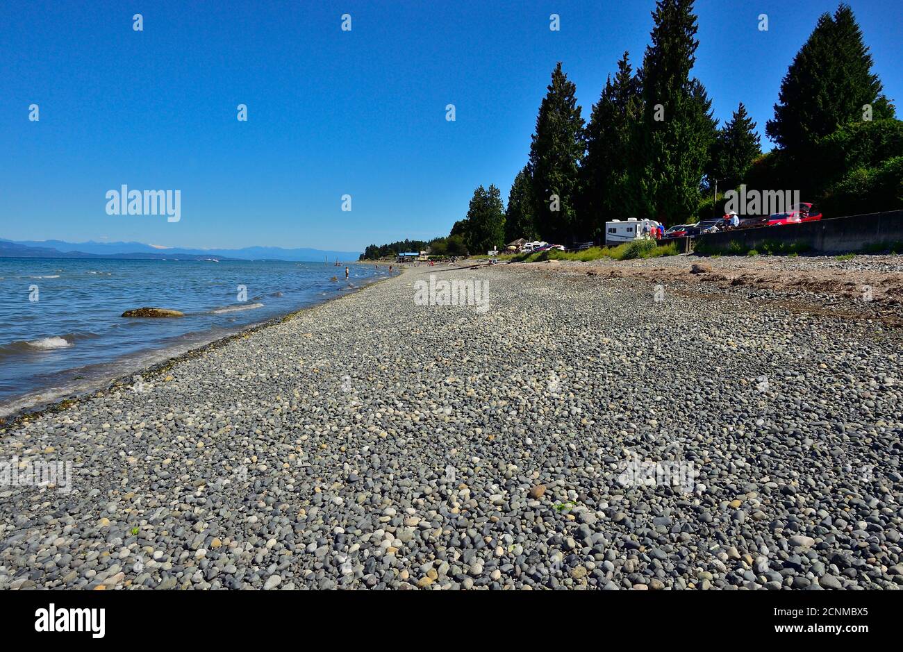 Menschen genießen einen schönen Frühlingstag, entspannen und spielen im Wasser am Qualicum Beach auf Vancouver Island British Columbia Kanada. Stockfoto
