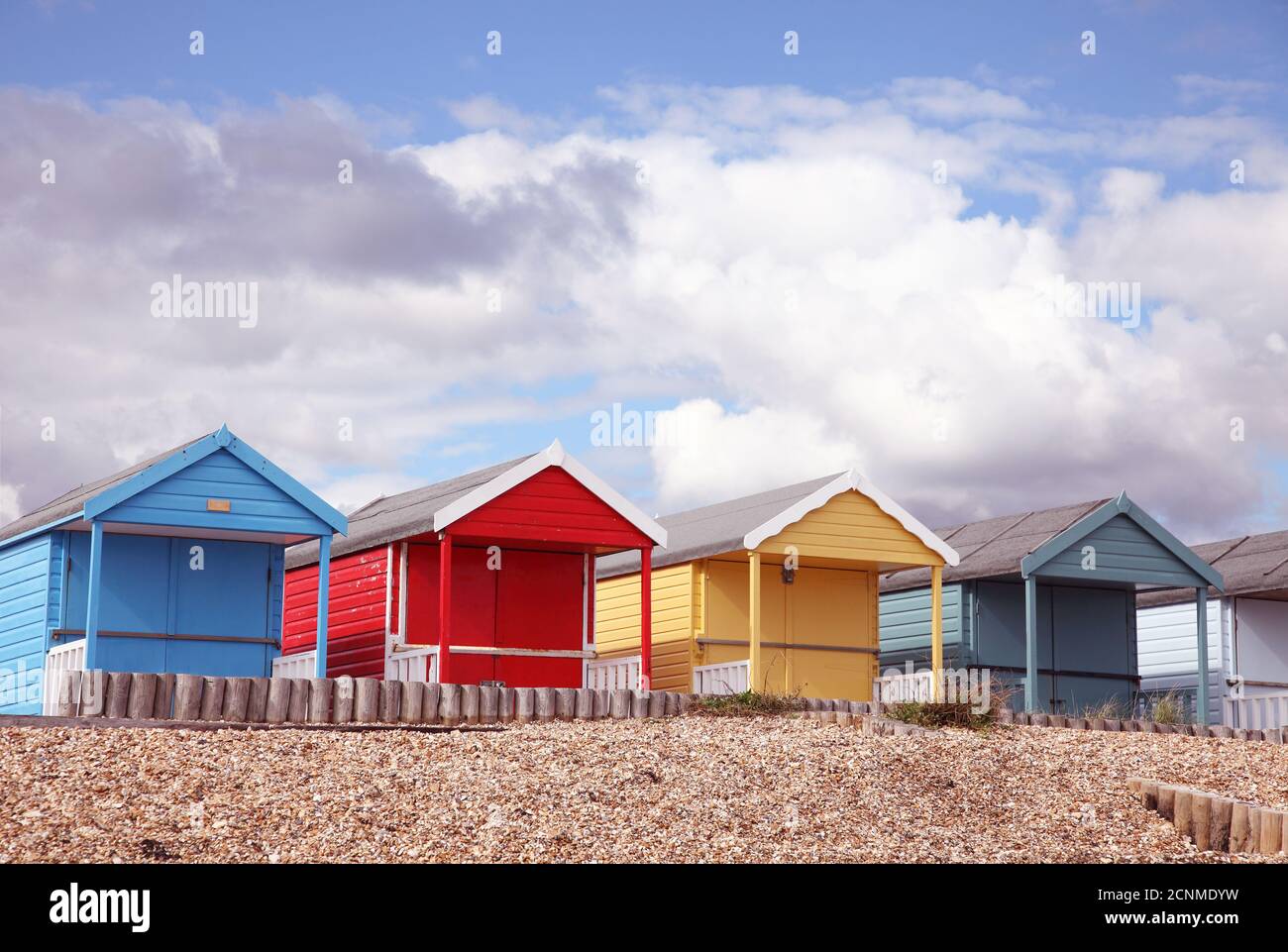 Primäre farbige, rote, gelbe, blaue Reihe von Strandhütten am englischen Strand, Calshot, Hampshire. Stockfoto
