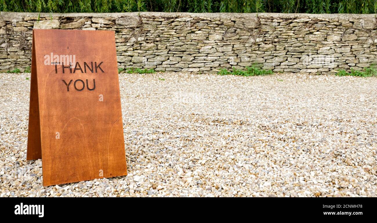 Hölzerne Dankesschild gegen Trockensteinmauer und cotswold Steinsplitterungen, Großbritannien Stockfoto