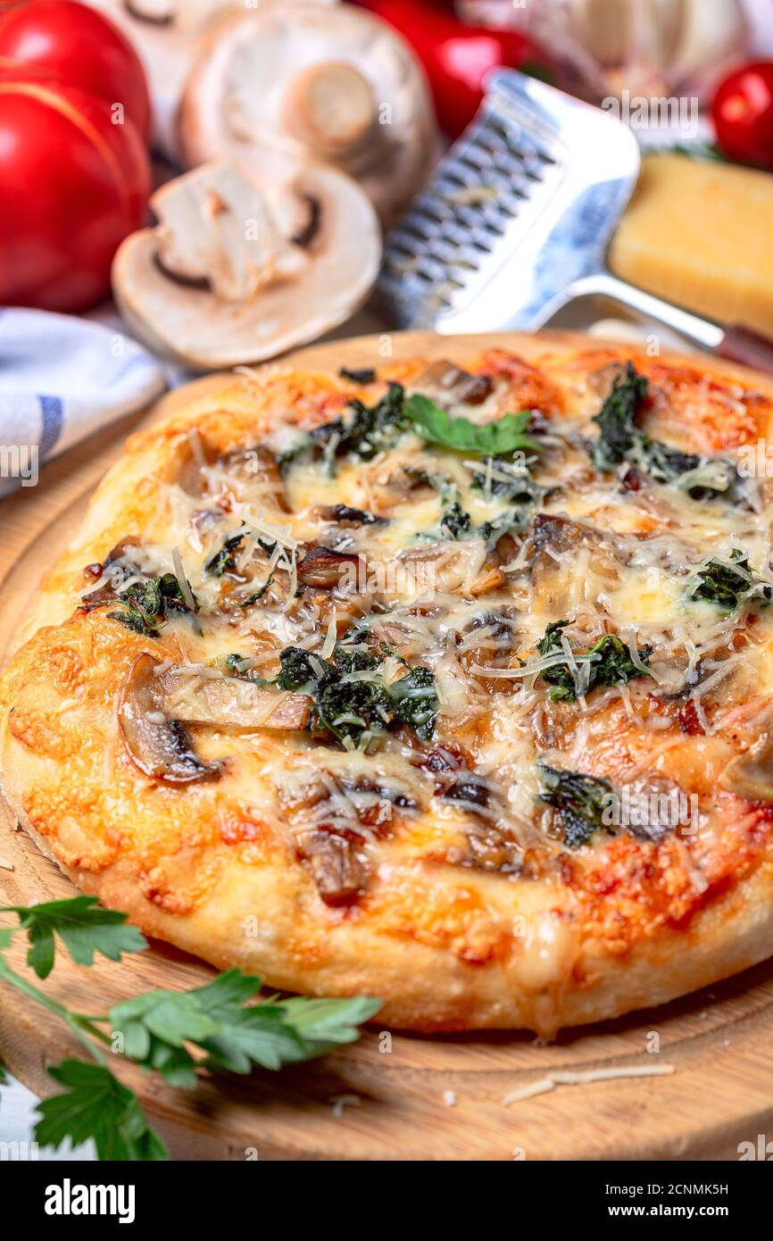 Hausgemachte Pizza mit Mozzarella, Pilzen und Spinat. Stockfoto