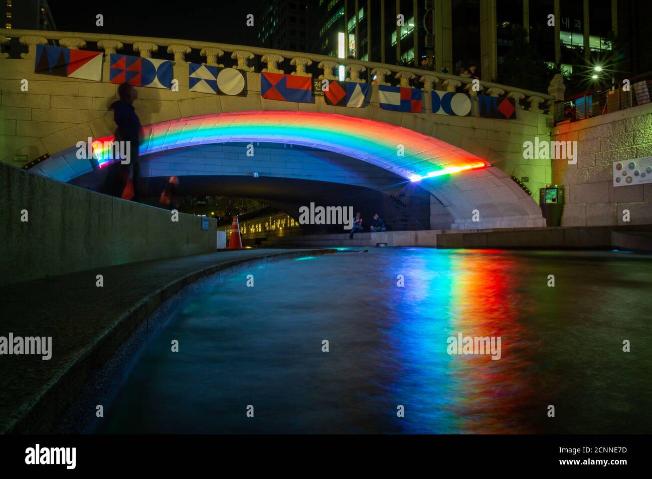 Ein Regenbogen, der sich über den Cheonggyecheon-Strom an der Gwangtonggyo-Brücke bei Nacht, Seoul, Südkorea, spiegelt Stockfoto