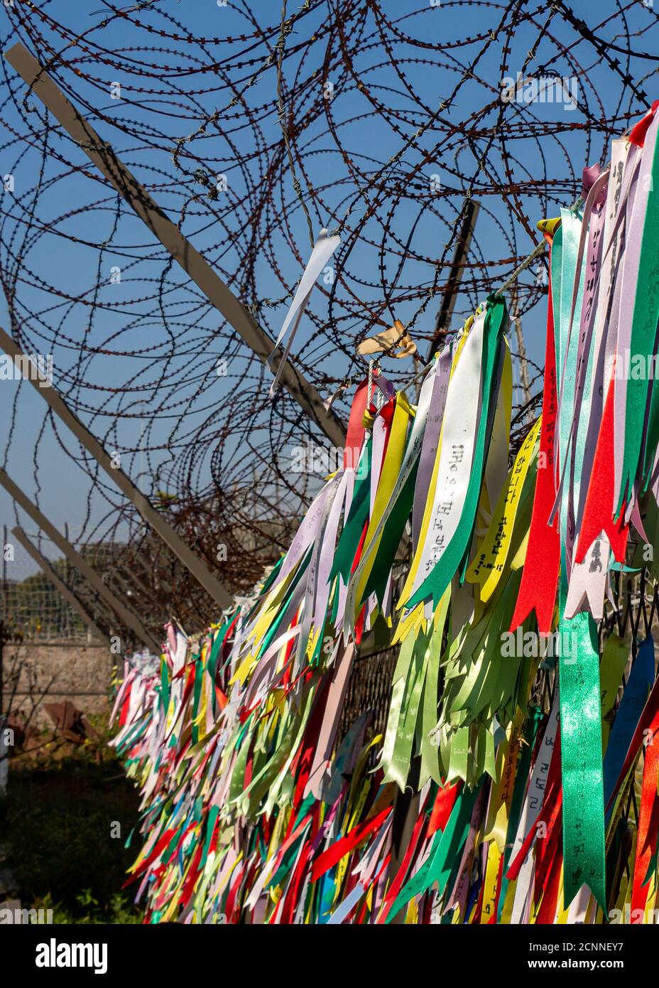 Gebetsbänder, die an einem Stacheldrahtzaun in der koreanischen Demilitarisierten Zone in Südkorea befestigt sind. Übersetzung: 'Frieden' Stockfoto