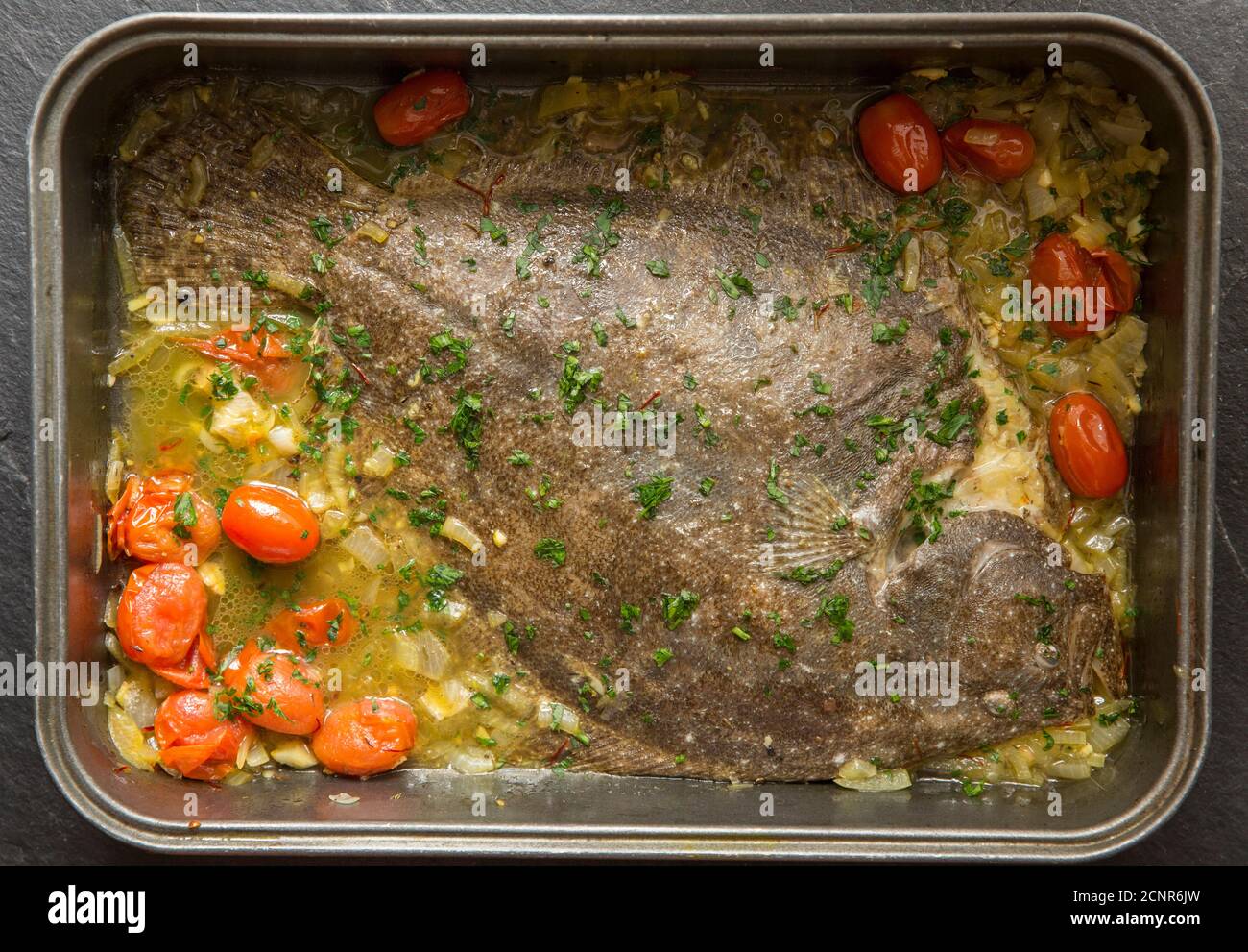 Ein ganzer Brill, Scophthalmus rhombus, der in Olivenöl mit Zwiebeln, Tomaten und Kräutern geröstet wurde. Dorset England GB Stockfoto