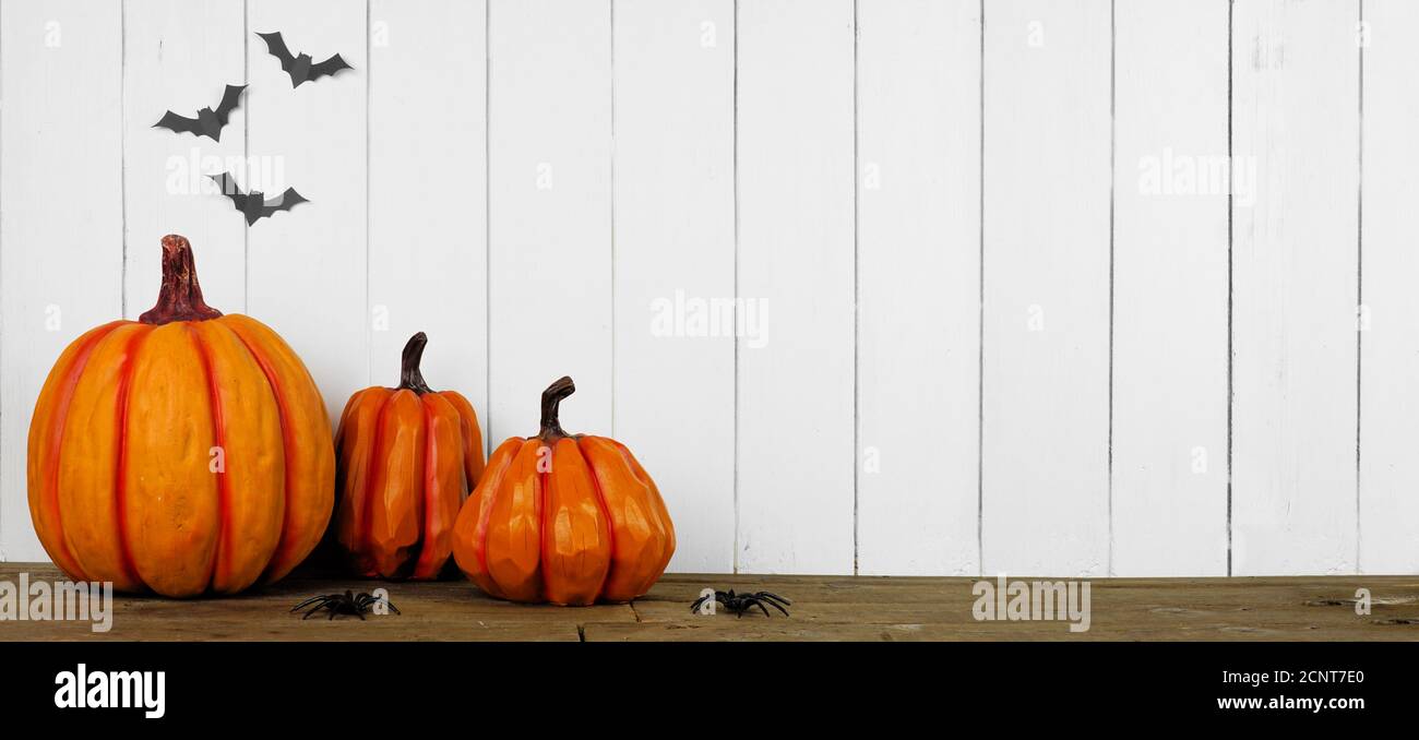 Halloween Kürbis Dekor auf einem Holzregal an einer weißen Holzpaneelwand mit Fledermäusen. Banner mit Kopierbereich. Stockfoto