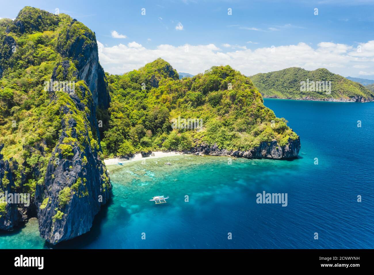 Luftdrohne Ansicht des tropischen Strandes mit einsames Boot auf Entalula Insel. Karst Kalksteinformation Berg umgeben von blauem Ozean und schönen cor Stockfoto