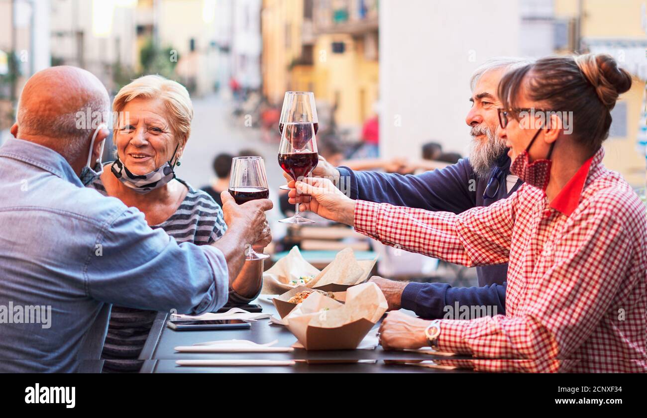 Gruppe alter Leute, die draußen essen und trinken - doppelt Datum mit Gesichtsmask auf - Fokusgläser Stockfoto