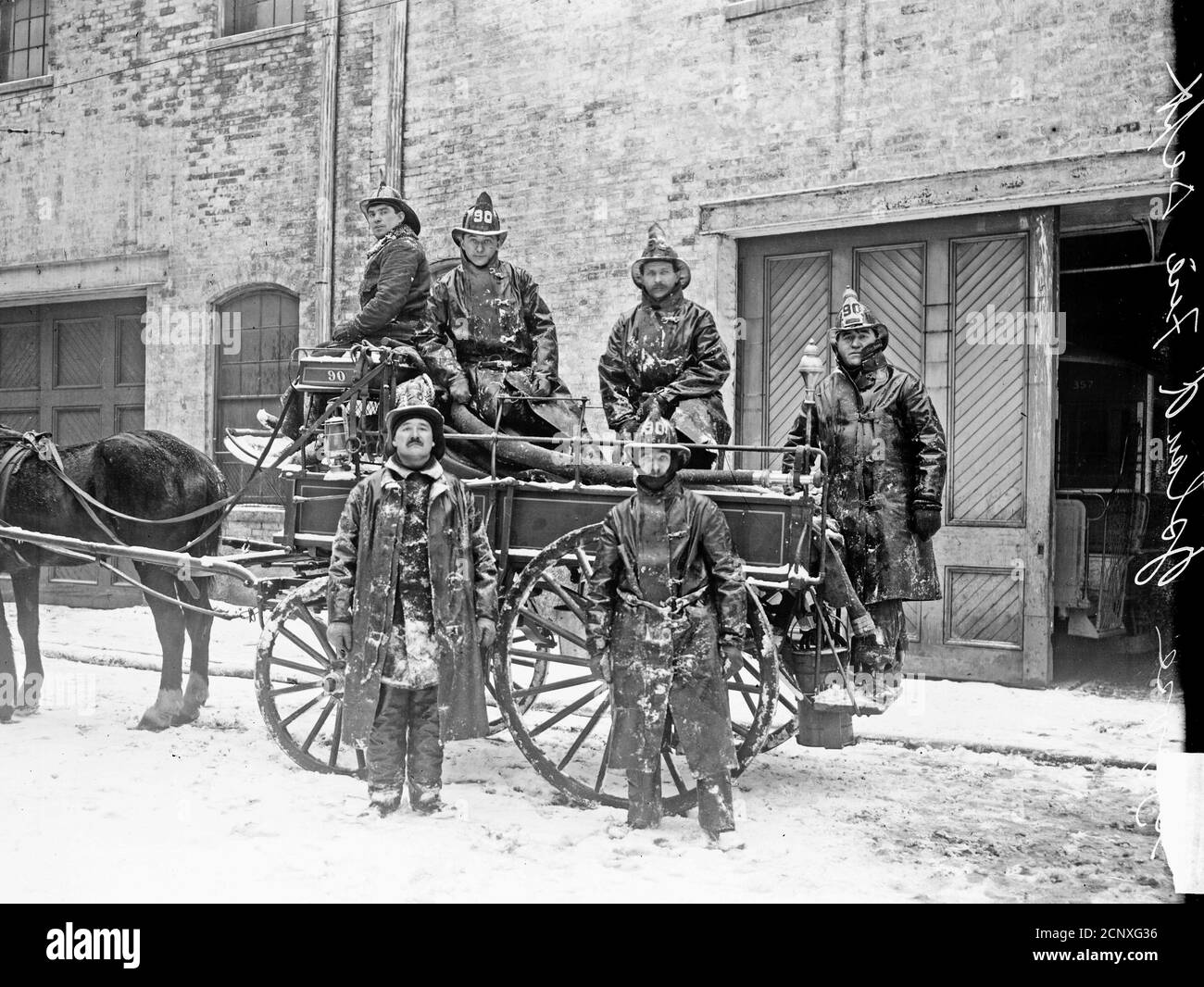 Sechs Mitglieder der Goose Island Fire Department stehen auf und vor einem von Pferden gezogenen Feuerwehrwagen, Chicago, Illinois Stockfoto