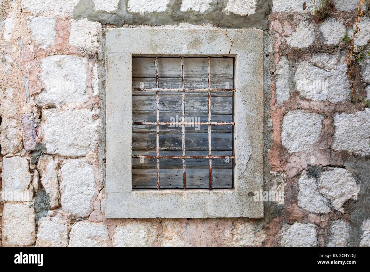 Verwitterte geschlossene Fenster mit rostigen Bars auf einem alten verlassenen Stein am Meer Haus. Stockfoto
