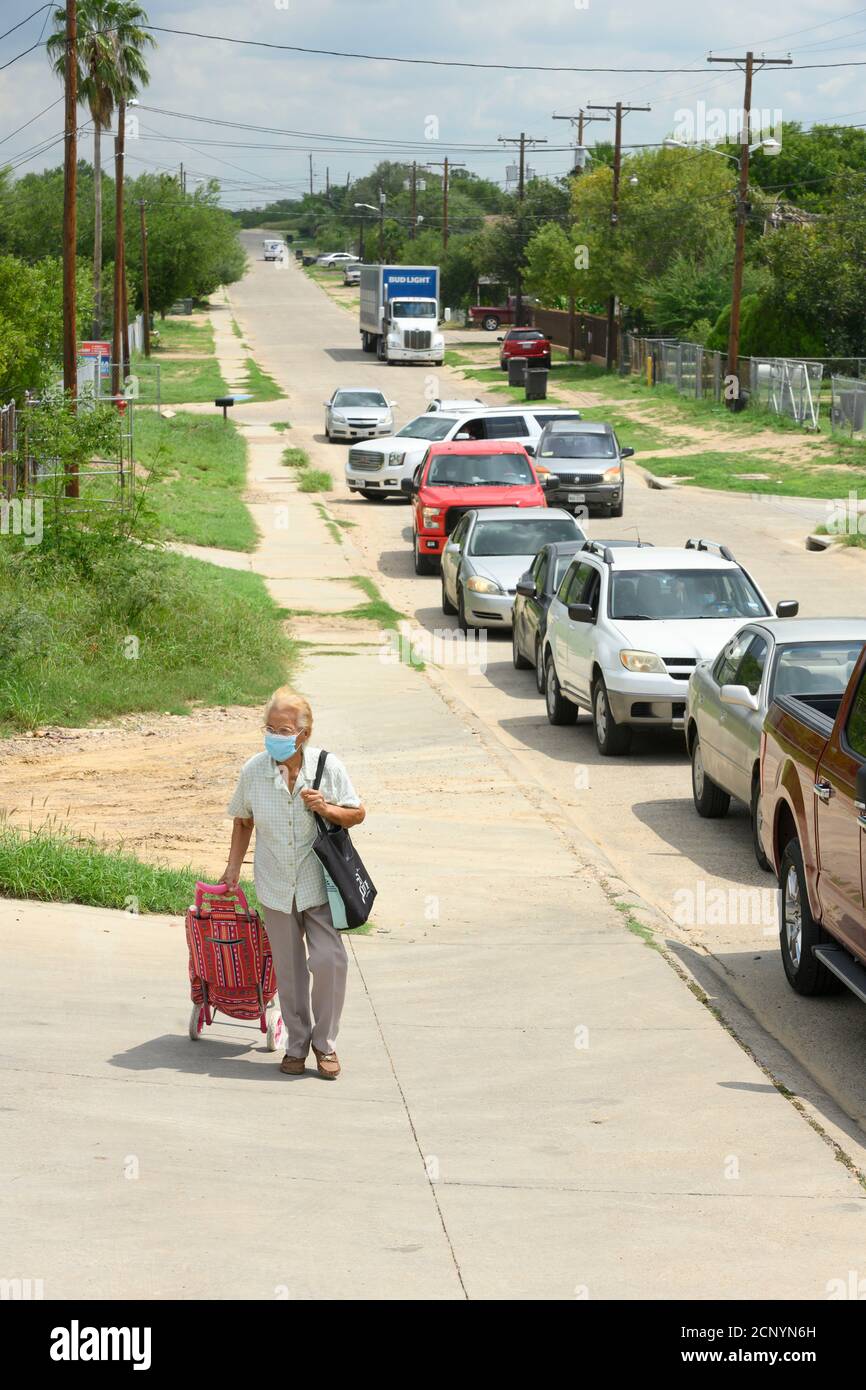 El Cenizo, TX USA 17. September 2020: Eine Frau mit einem Einkaufswagen geht zu einem Drive-up Foor Distribution Site für Bewohner der colonia von El Cenizo 10 Meilen südlich von Laredo entlang der Texas-Mexiko-Grenze. Etwa 450 Familien werden zweimal in der Woche mit Heftklammern und frischem Obst in einer von der lateinamerikanischen lutherischen Mission (LALM) gesponserten Bemühung serviert. Aufgrund der Coronavirus-Pandemie ist die Verteilung nun (meist) ein sozial distanziertes Drive-Through-Ereignis, bei dem Freiwillige und Kunden alle Gesichtsbezüge tragen. Kredit: Bob Daemmrich/Alamy Live Nachrichten Stockfoto
