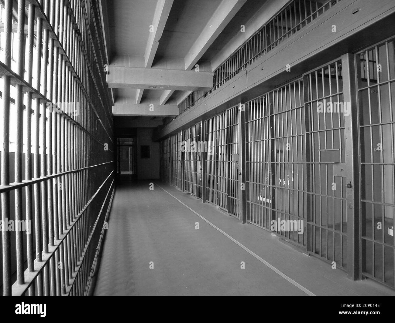 Schwarz-Weiß-Ansicht der alten Gefängniszellen mit Metallstangen in einer geschlossenen heruntergekommenen staatlichen Einrichtung. Stockfoto