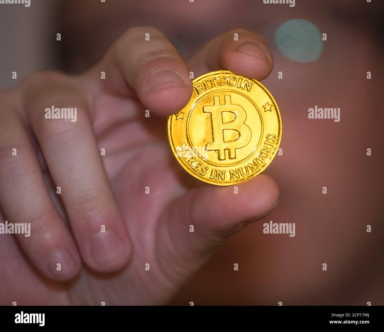 Hält eine goldene Bitcoin-Münze in der Hand, die die elektronische Währung darstellt Stockfoto