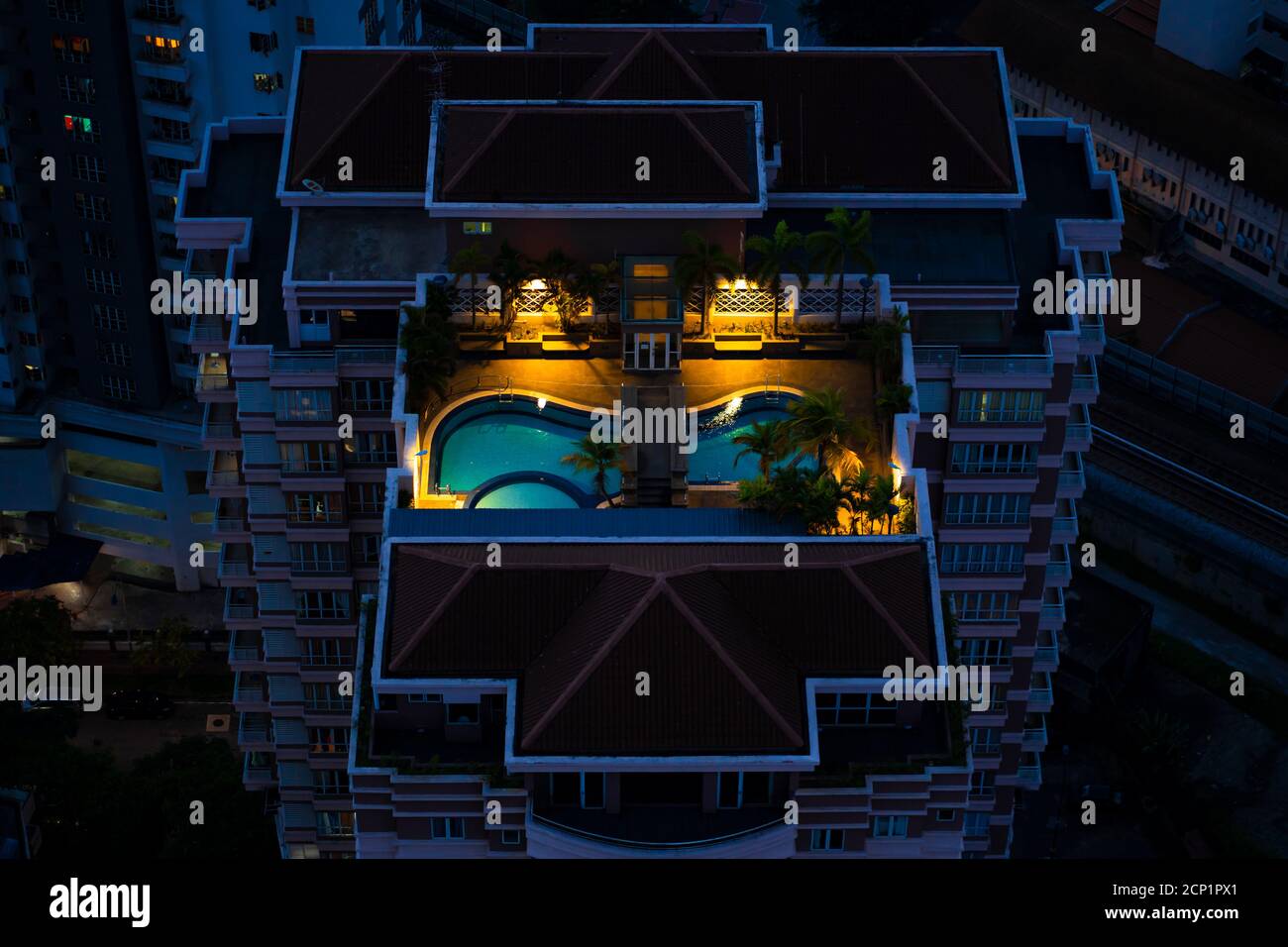 Nachts Blick von oben auf eine mehrstöckige Wohnanlage mit einem Pool auf dem Dach. Stockfoto
