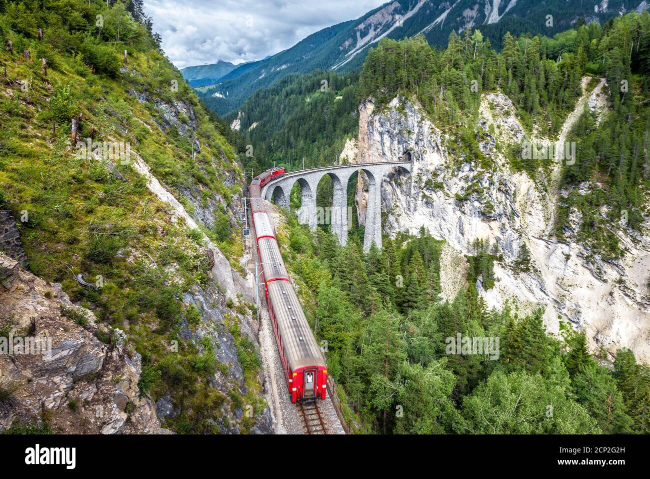 Der Zug fährt auf dem Landwasser Viadukt, Filisur, Schweiz. Dieser Ort ist Wahrzeichen der Schweizer Alpen. Landschaftlich schöner Blick auf die hohe Eisenbahnbrücke im Sommer. Berg Stockfoto