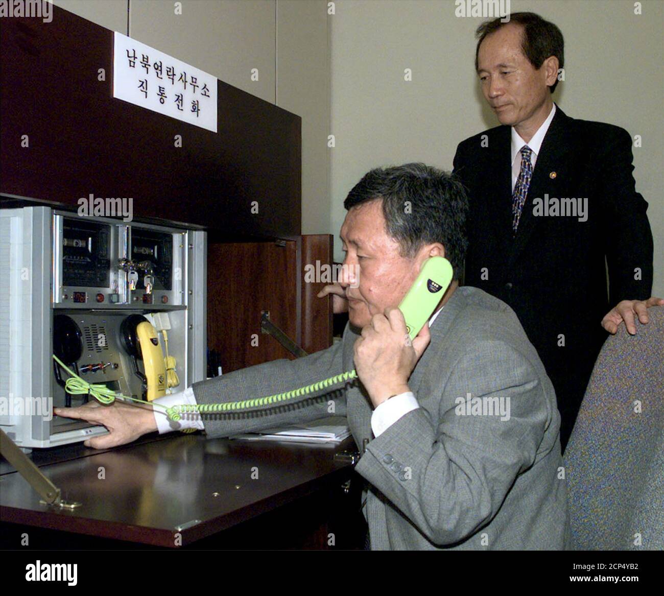 Der südkoreanische Vereinigungsminister Park Jae-Kyu (R) beobachtet, wie ein Beamter, Oh sei Eung, nach der Wiedereröffnung des Süd-Nord-Verbindungsbüros im Grenzdorf Panmunjom zwischen den beiden Koreas am 14. August 2000 einen Direktanruf abgibt. Hunderte von älteren Koreanern, die vor einem halben Jahrhundert durch den Koreakrieg aus ihren Familien gerissen wurden, werden diese Woche in beispiellosen Treffen, die Trauma und Trauer sowie Freude und Aufregung hervorgerufen haben, kurz mit ihren Angehörigen vereint sein. DL Stockfoto