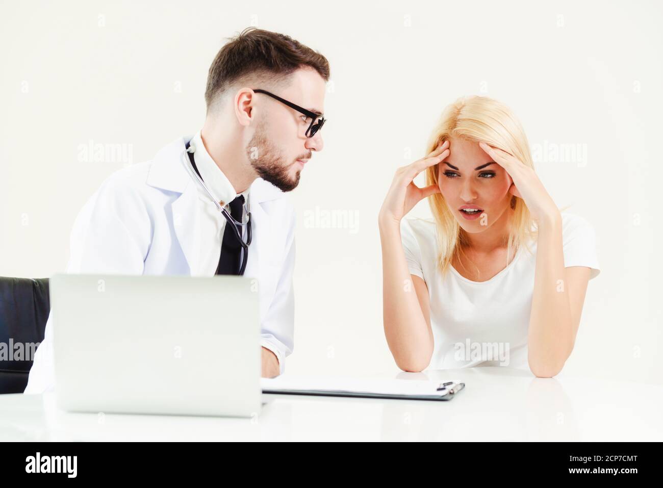 Männlicher Arzt spricht mit weiblichen Patienten im Krankenhaus Büro, während Blick auf die Patienten Gesundheitsdaten auf Laptop-Computer auf dem Tisch. Gesundheitswesen und Stockfoto