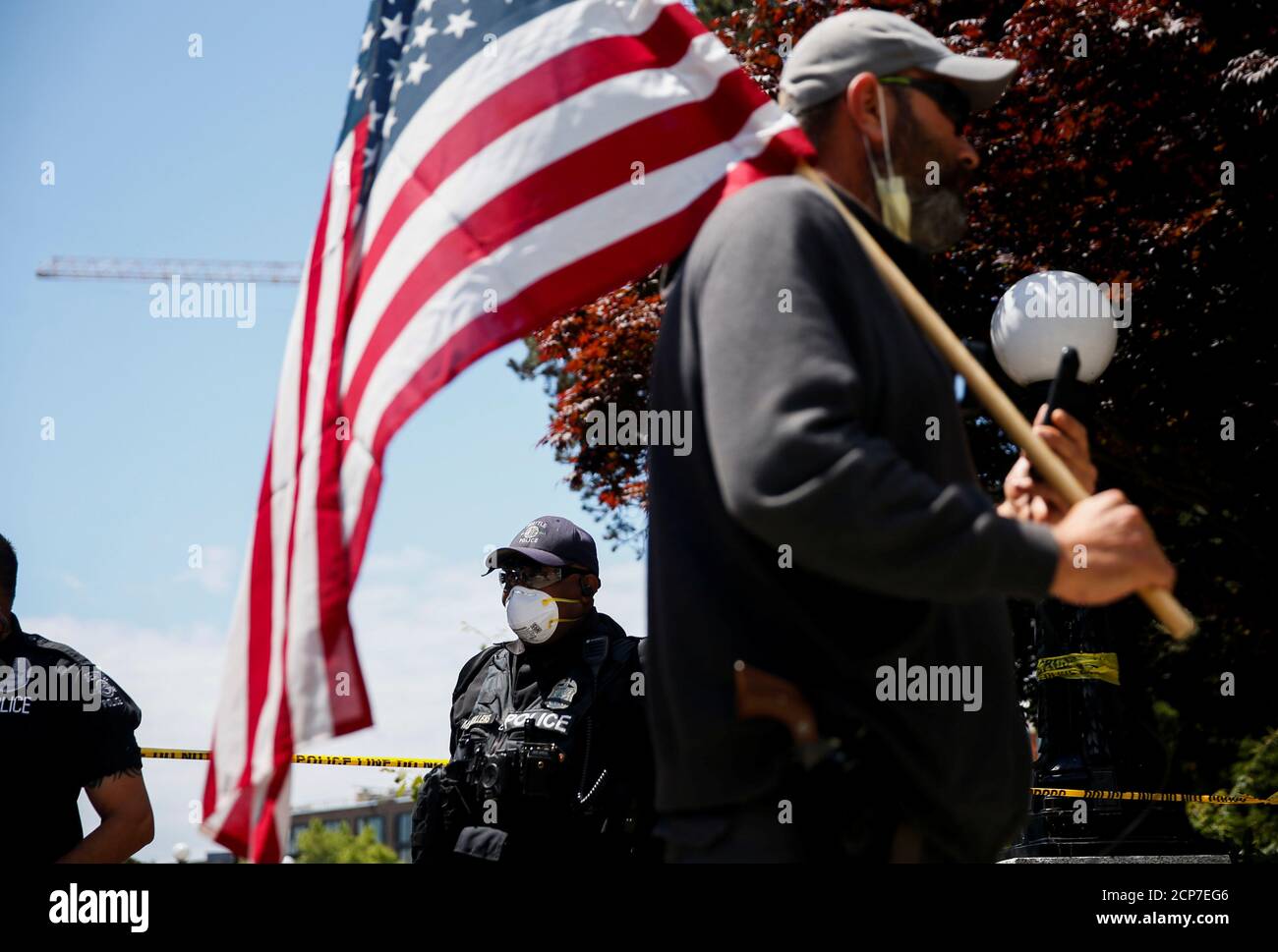 Ein Mann mit einer amerikanischen Flagge geht von Seattle Polizeibeamten, die einen geschlossenen Cal Anderson Park im ehemaligen Capitol Hill besetzten Protestgebiet (CHOP) am 4. Juli Feiertag in Seattle, Washington, USA bewachen. 4. Juli 2020. REUTERS/Lindsey Wasson Stockfoto