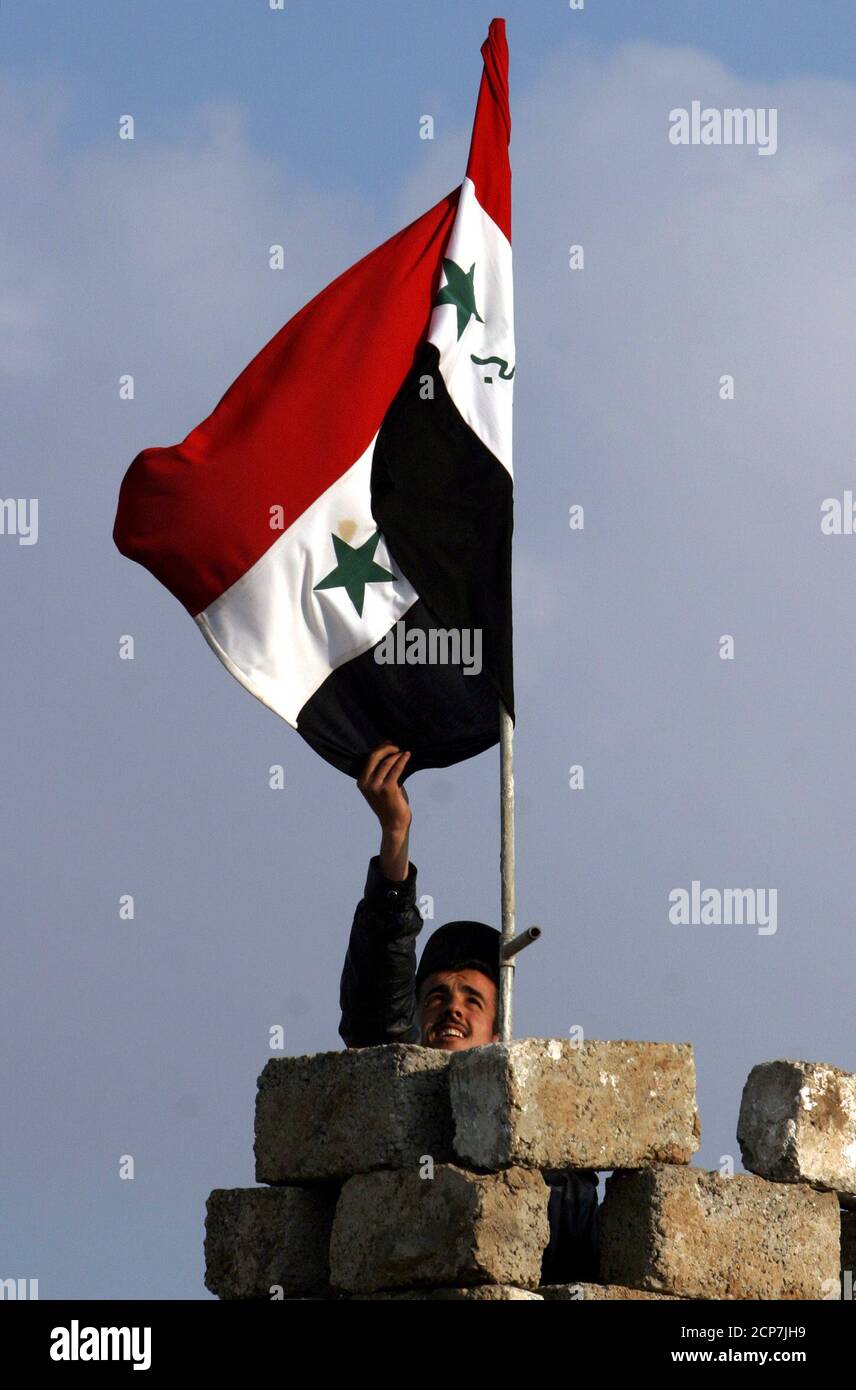Iraqi Civil Defense Corps Soldat passt eine irakische Flagge an einem Kontrollpunkt im nördlichen Irak Stadt Mosul, etwa 400 km nordwestlich von Bagdad 7. Januar 2004. REUTERS/Alexander Demianchuk AD/CRB Stockfoto