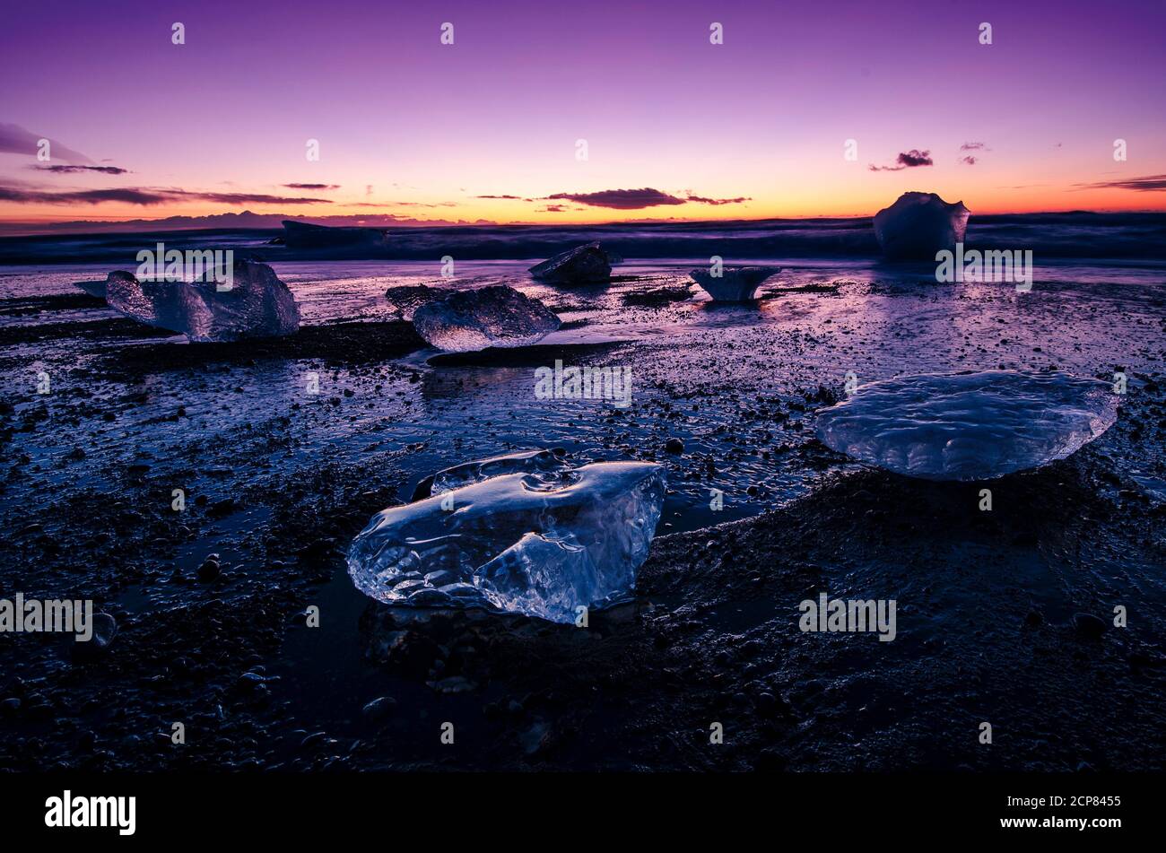 Sonnenaufgang über dem Meer in Island, am Diamond schwarzen Sandstrand mit Licht, das die Eisberge am Strand trifft. Stockfoto