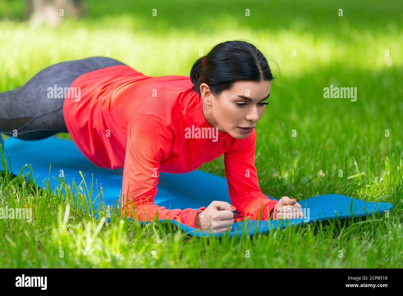 Frau, die Plank-Übung auf einem Gras im Stadtpark tut. Nahaufnahme. Stockfoto