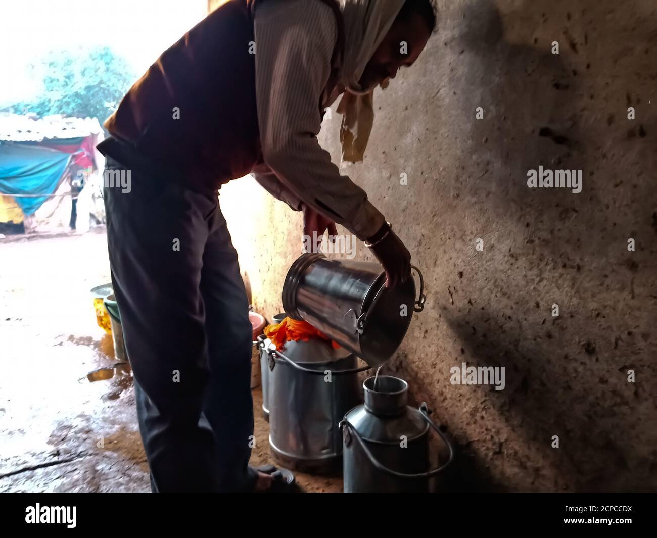 DISTRIKT KATNI, INDIEN - 04. JANUAR 2020: Ein Milchbauer sammelt Milch auf Container in seiner lokalen Milchfarm, einer indischen Farmszene. Stockfoto