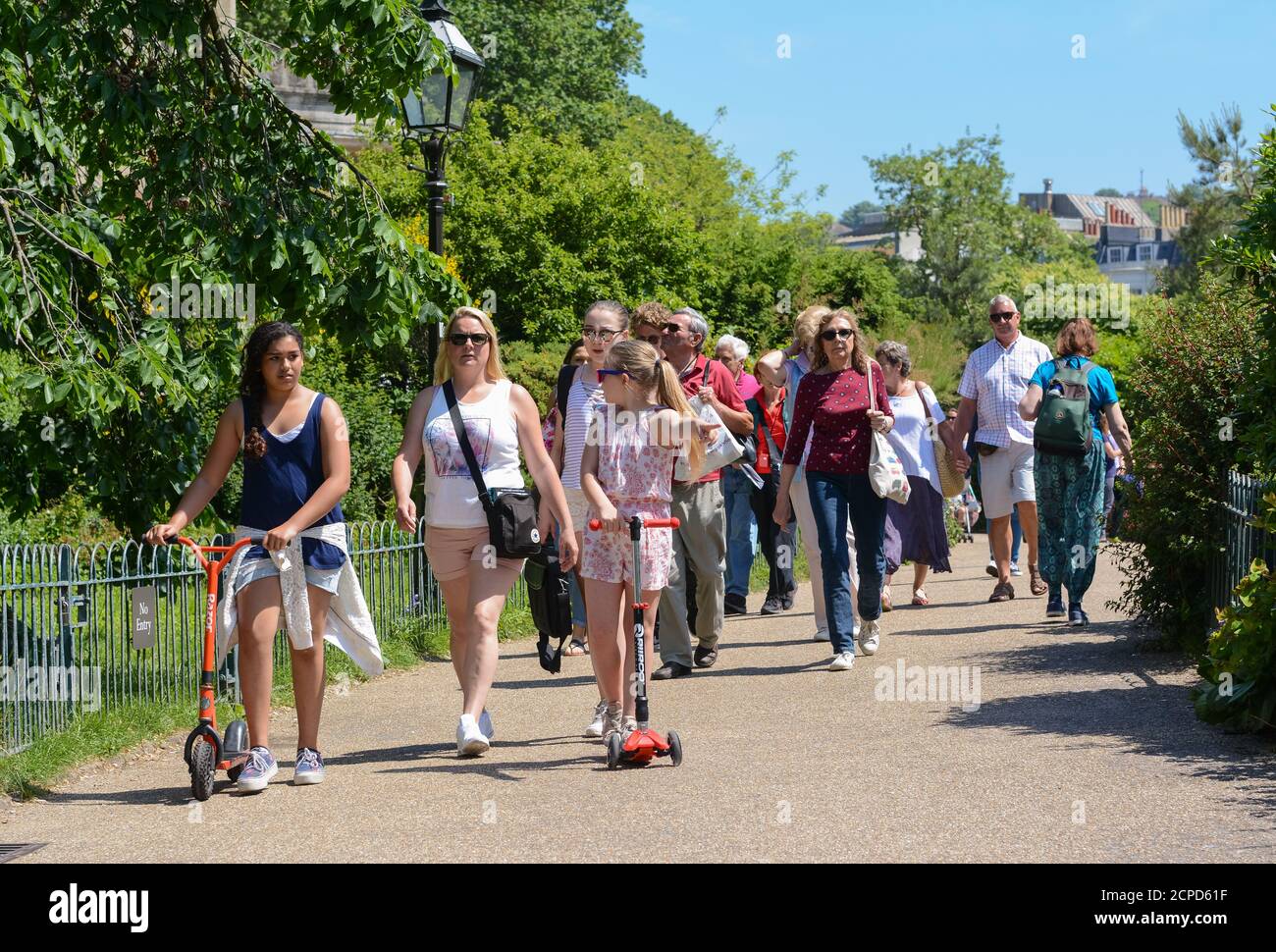Menschenmassen, die an einem heißen Sommertag in Brighton, East Sussex, England, durch den Park der Royal Pavilion Gardens spazieren. Stockfoto