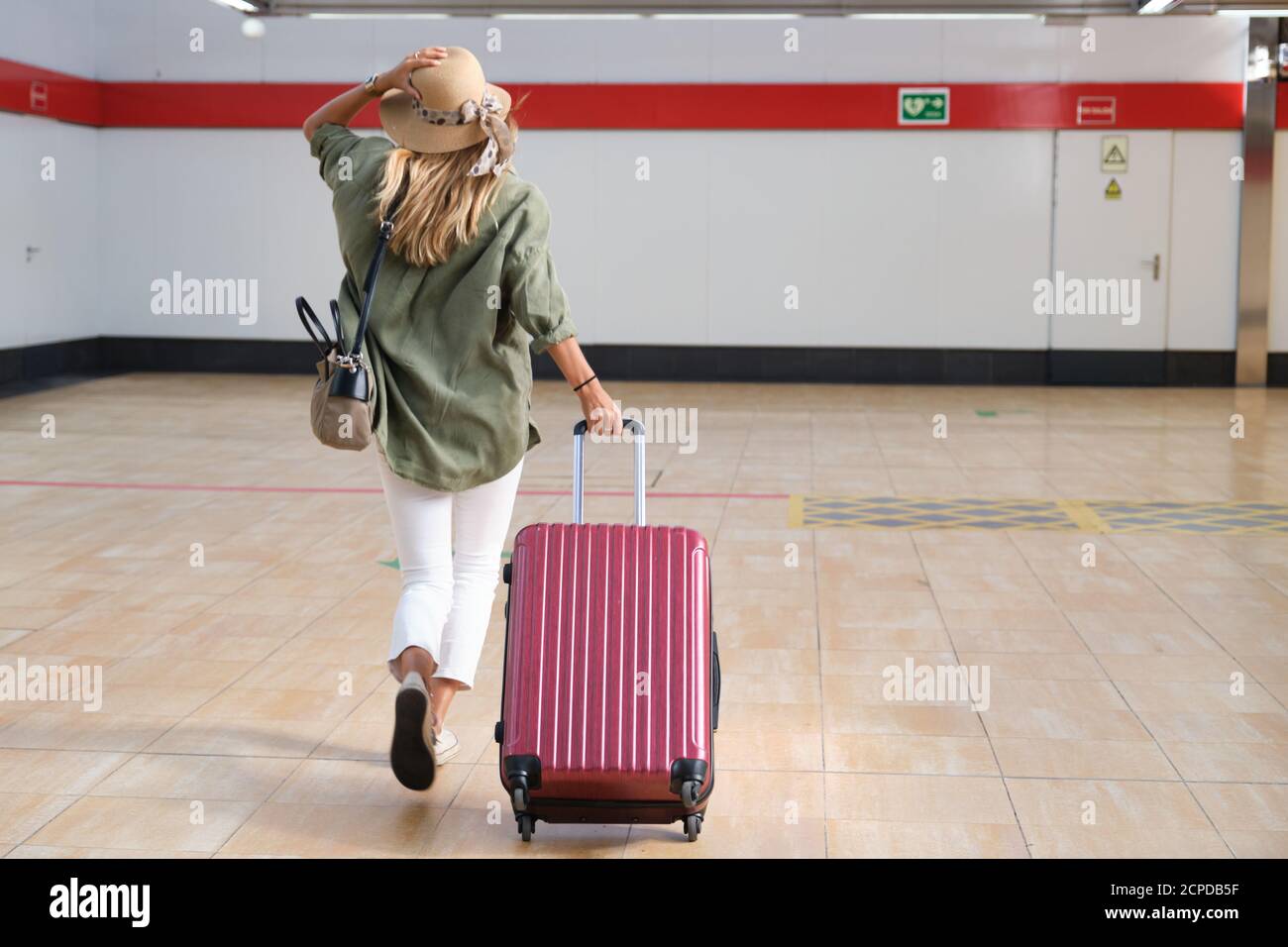 Junge Frau läuft, weil sie den Zug verliert, sie trägt einen Hut und einen Koffer. Reisekonzept. Stockfoto