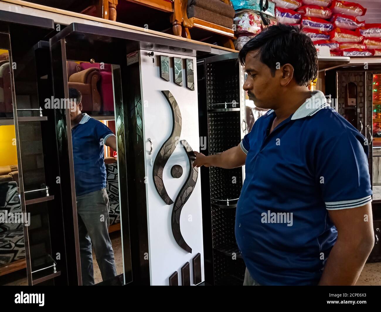 BEZIRK KATNI, INDIEN - 08. JANUAR 2020: Ein indischer männlicher Ladenbesitzer zeigte hölzerne Ankleidereiset auf Möbelgeschäft. Stockfoto