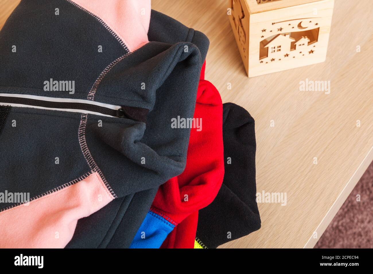 Gestapelte bunte Fleece Jacken auf einem Holztisch, Draufsicht Stockfoto Gestapelte bunte Fleece Jacken auf einem Holztisch, Draufsicht Stockfoto