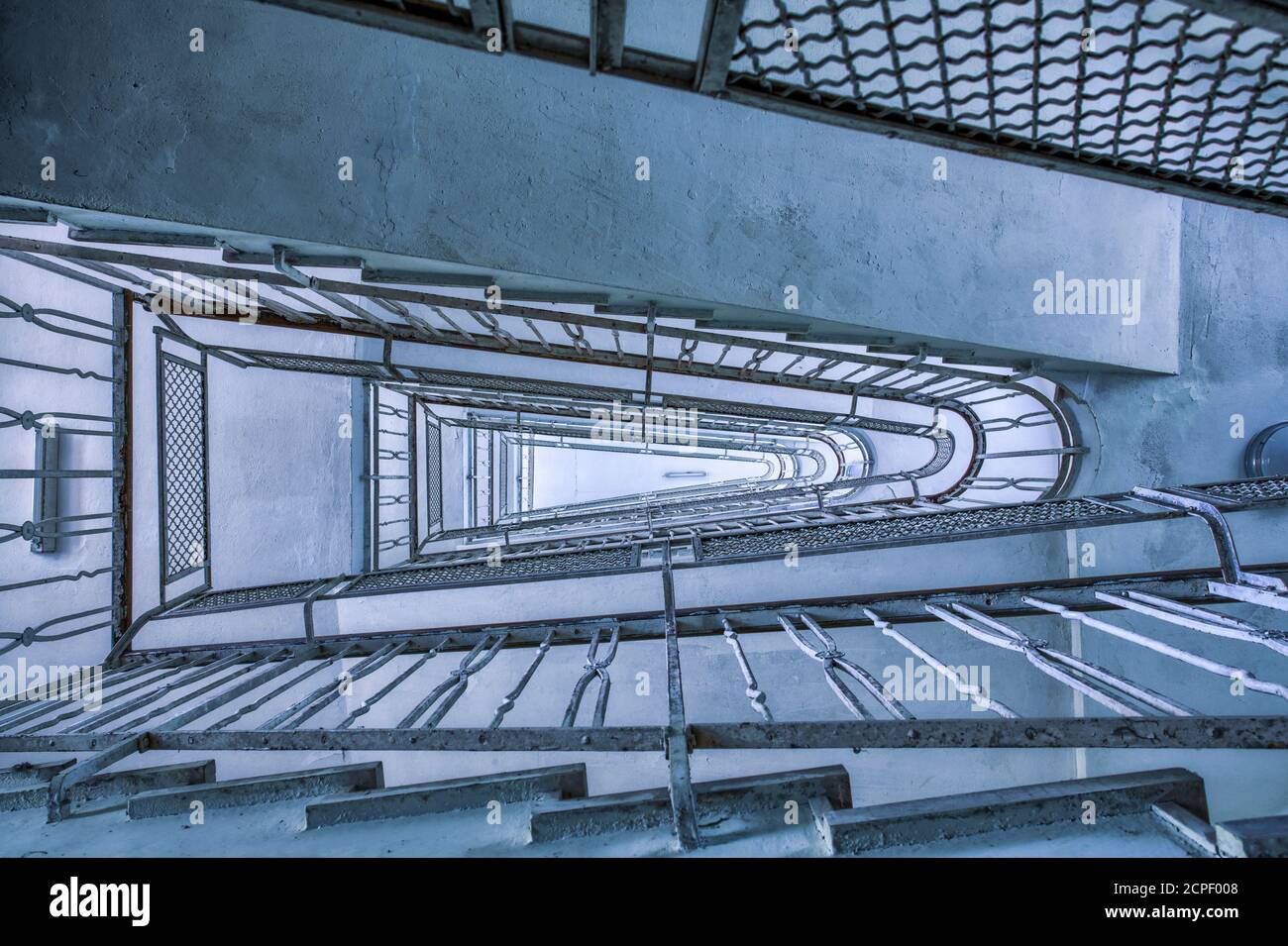 Blick von unten auf die Treppe mit Eisengeländer, hypnotisches Bild, kalter Ton Stockfoto