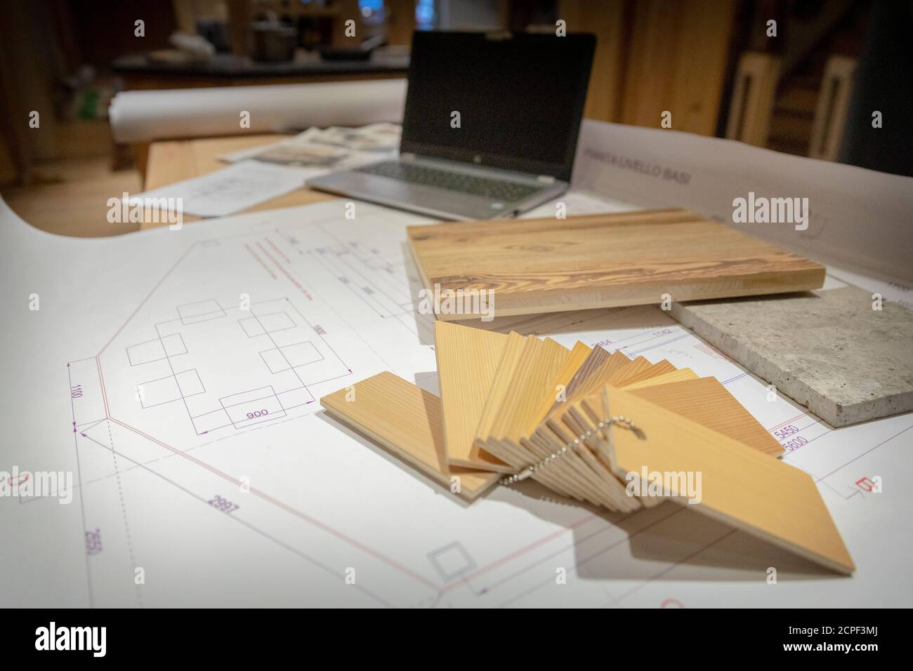 Zimmerei, Holzmöbel, technische Zeichnungen und Muster verschiedener Holzarten mit einem Laptop unter einem Schreibtisch Stockfoto