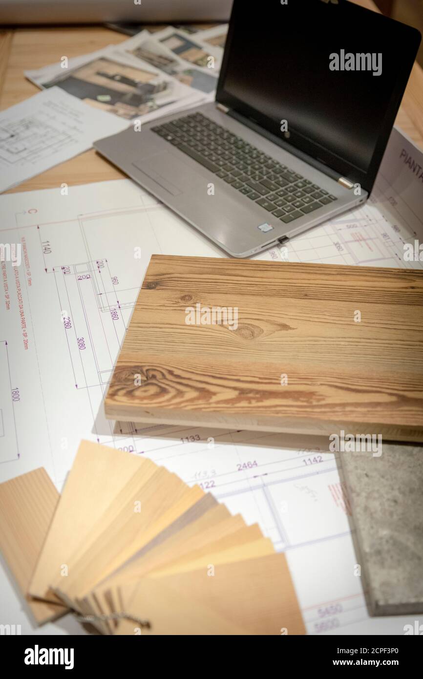 Zimmerei, Holzmöbel, technische Zeichnungen und Muster verschiedener Holzarten mit einem Laptop unter einem Schreibtisch Stockfoto