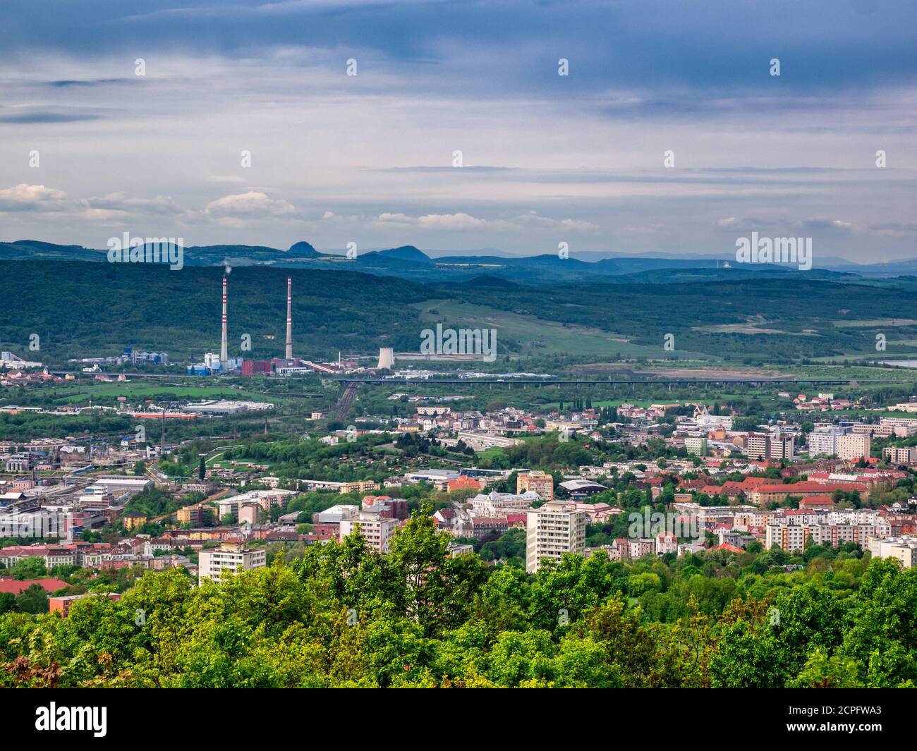 Blick vom Berg auf die Landschaft mit der Stadt Im Tal und in der Fabrik mit zwei hohen Schornsteinen Hinter der Stadt Stockfoto