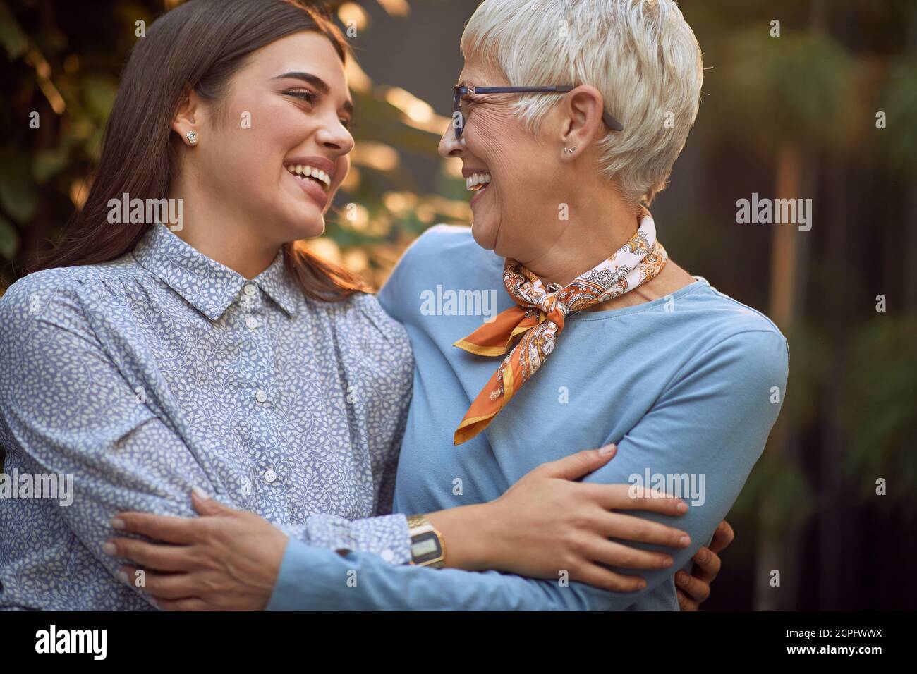Erwachsene Mutter und Tochter umarmen, einander schauen, lächeln Stockfoto