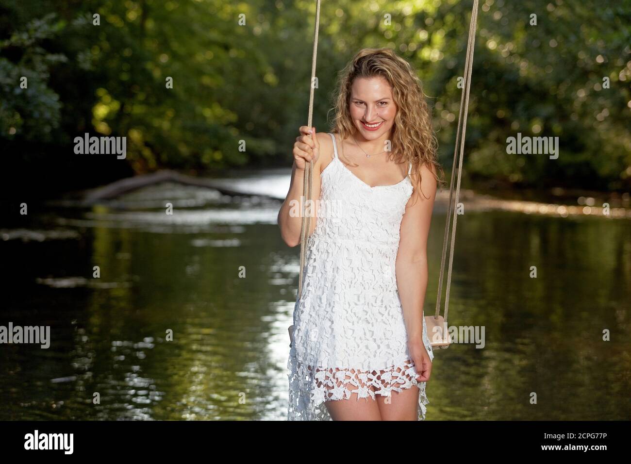Schöne Frau in weißem Kleid auf einer Schaukel Stockfoto
