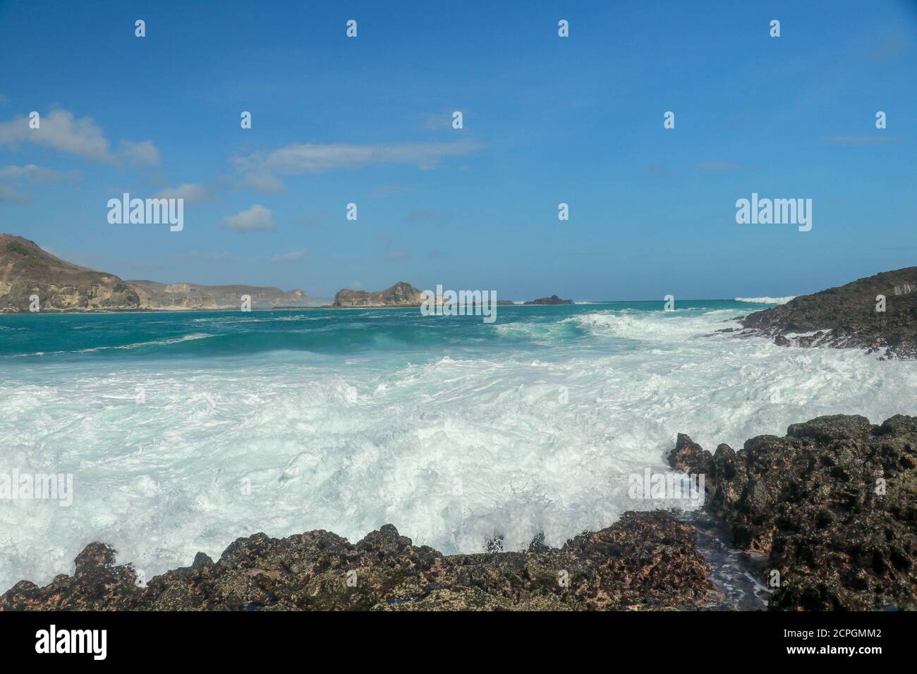 Wellen, die auf scharfen Klippen des Tanjung Aan Strandes plantschen. Gefährliches Phänomen an einem himmlischen Strand. Wasser wird durch die Stärke der Zerkleinerung sprudelt Stockfoto