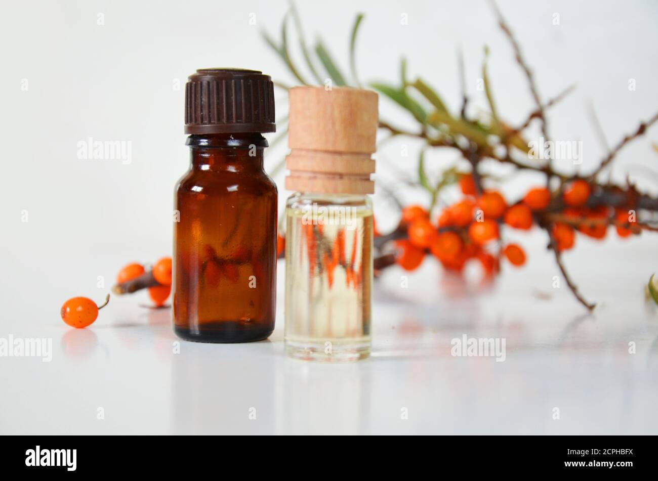 Sanddornbeeren Cluster und Ölflasche Glas isoliert auf a Weißer Hintergrund Stockfoto