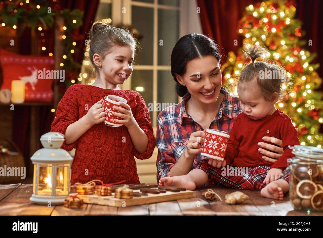 Frohe Weihnachten und frohe Feiertage. Zeit der Familie Teeparty. Mutter und ihre Kinder Töchter trinken warmen Tee mit Weihnachtsplätzchen. Stockfoto