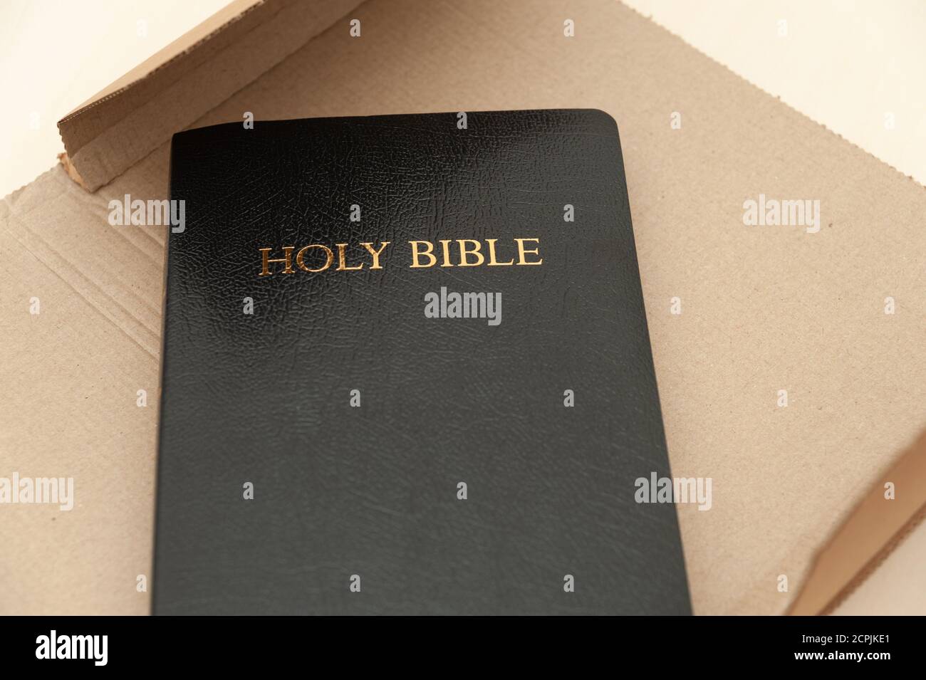 Versandkarton mit der Heiligen Bibel, die geöffnet wird. Draufsicht. Nahaufnahme. Horizontale Aufnahme. Stockfoto