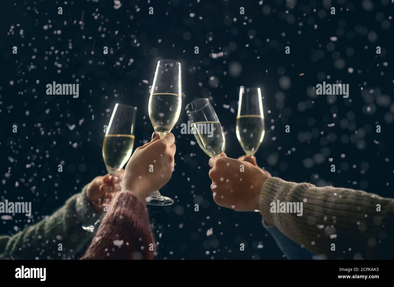 Frohe Weihnachten und ein glückliches neues Jahr! Hände von Menschen mit Weingläsern klirren in verschneiten Winternacht. Stockfoto