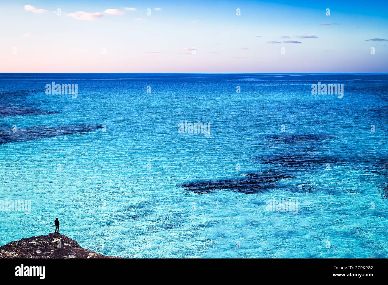 Ein Mann, der beim Blick auf den weiten Blauen Ozean steht Stockfoto