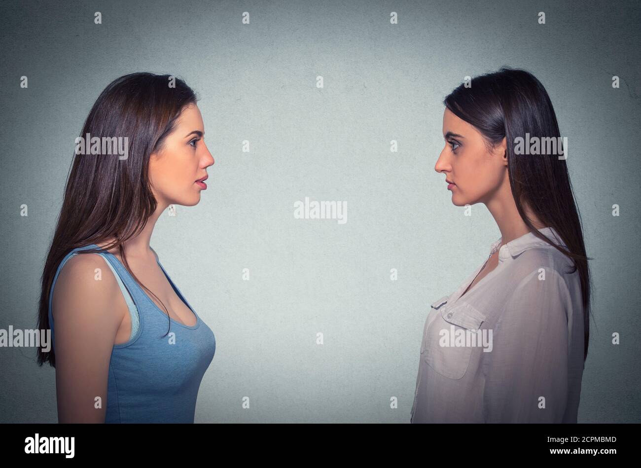 Seitenprofil zwei junge Frauen schauen sich isoliert an Auf grauem Hintergrund Stockfoto